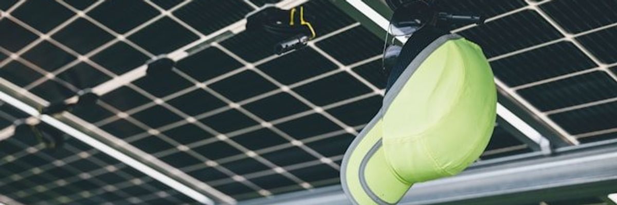 A lime green hat hanging on the underside of solar panels