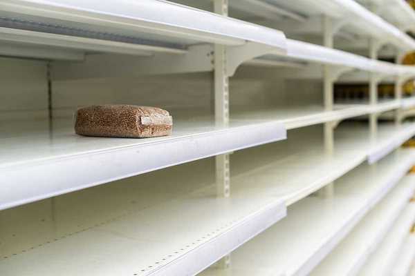 A lone package of grain on otherwise empty supermarket shelves