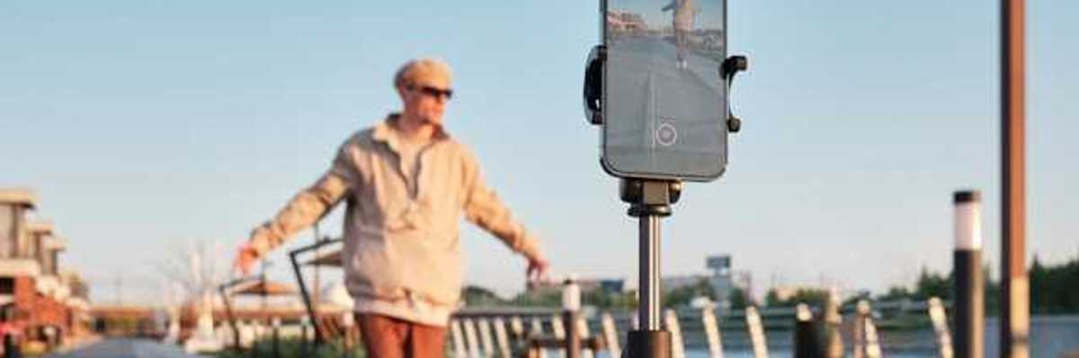 A male influencer standing in front of his phone on a tripod shooting a video