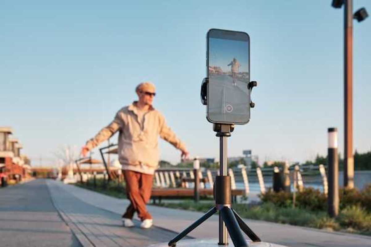 A male influencer standing in front of his phone on a tripod shooting a video