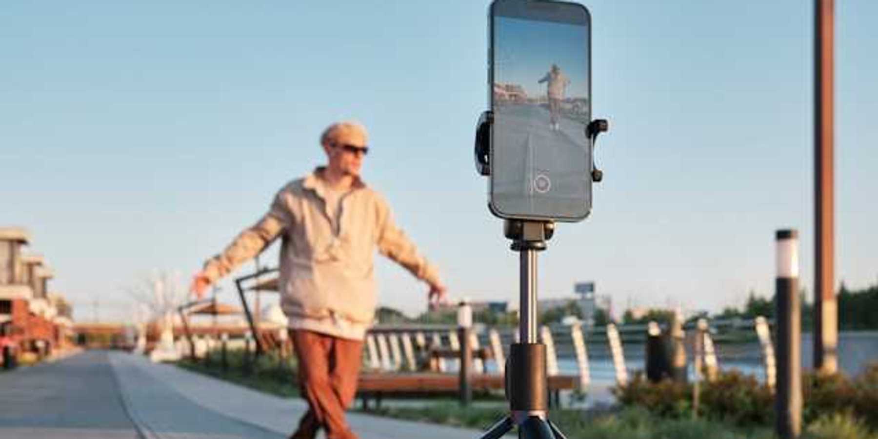 A male influencer standing in front of his phone on a tripod shooting a video