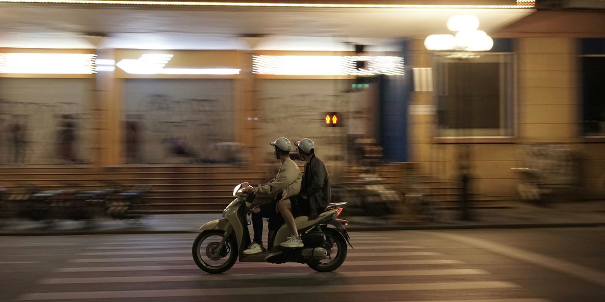 a man and a woman riding a motorcycle down a street.