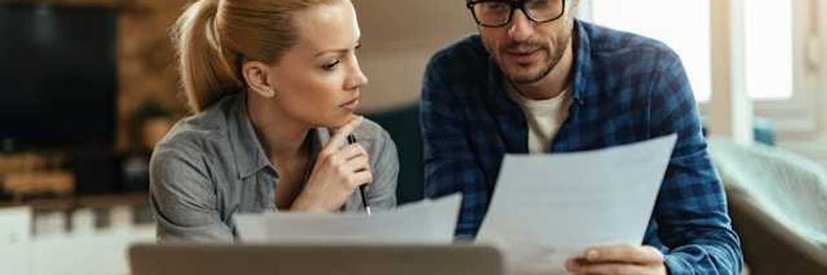 A man and woman at home looking at bills