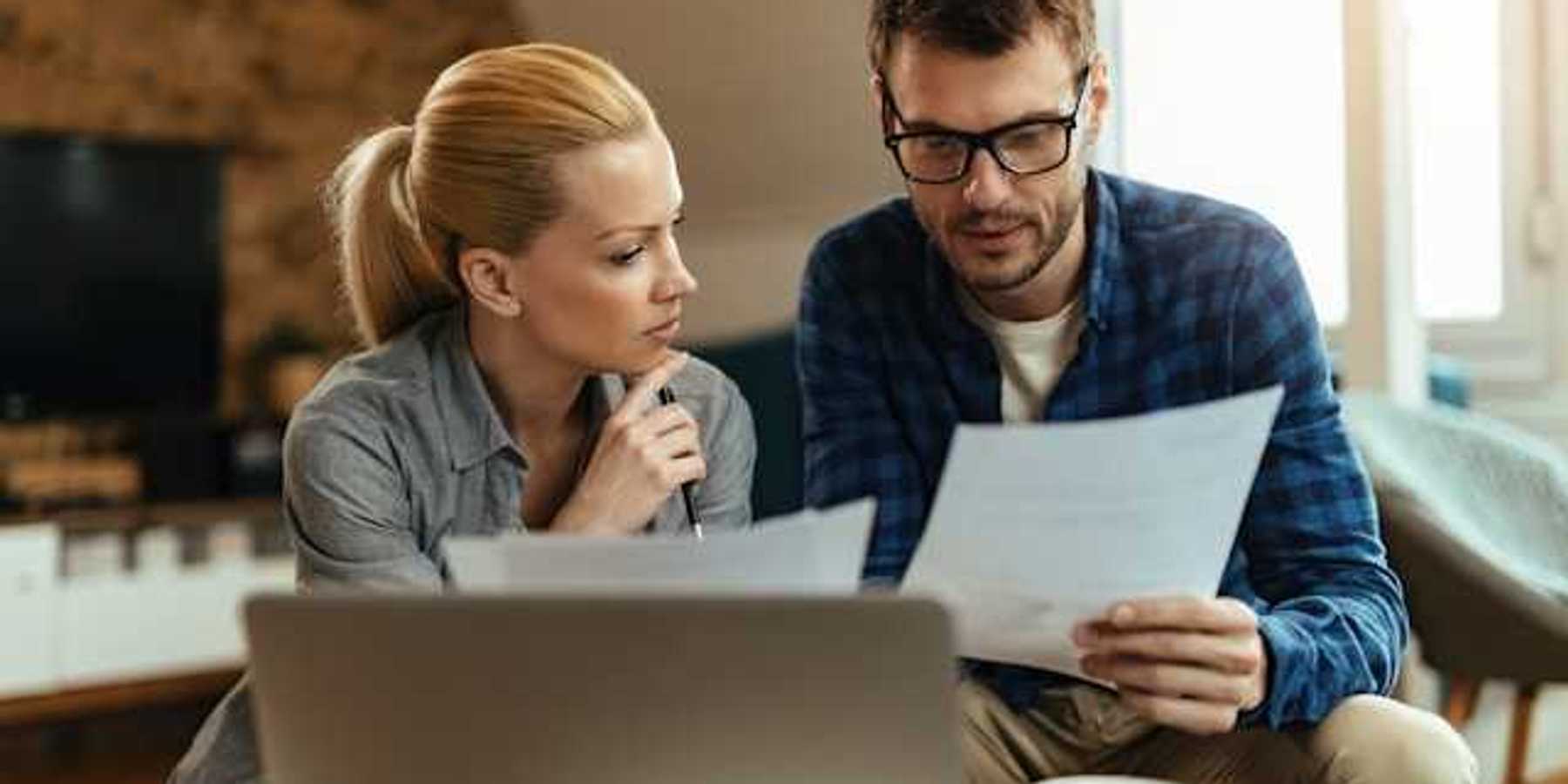 A man and woman at home looking at bills