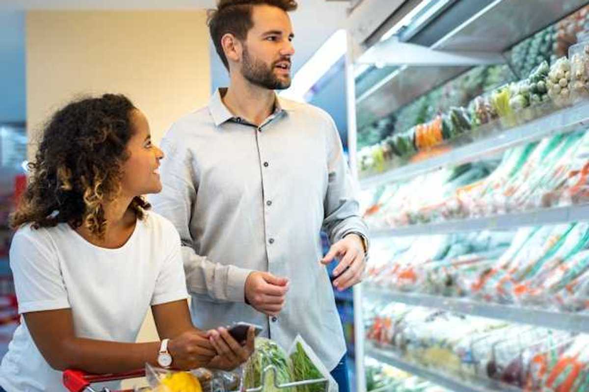 A man and woman in a grocery store looking at produce
