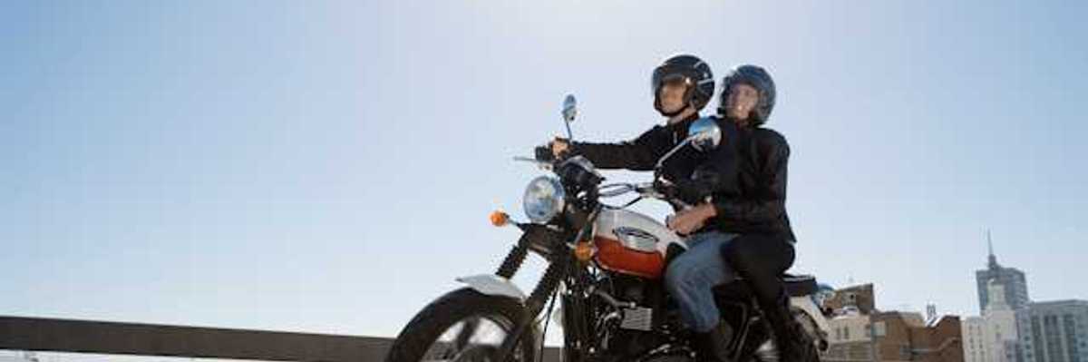 A man and woman riding on a motorcycle on a city street