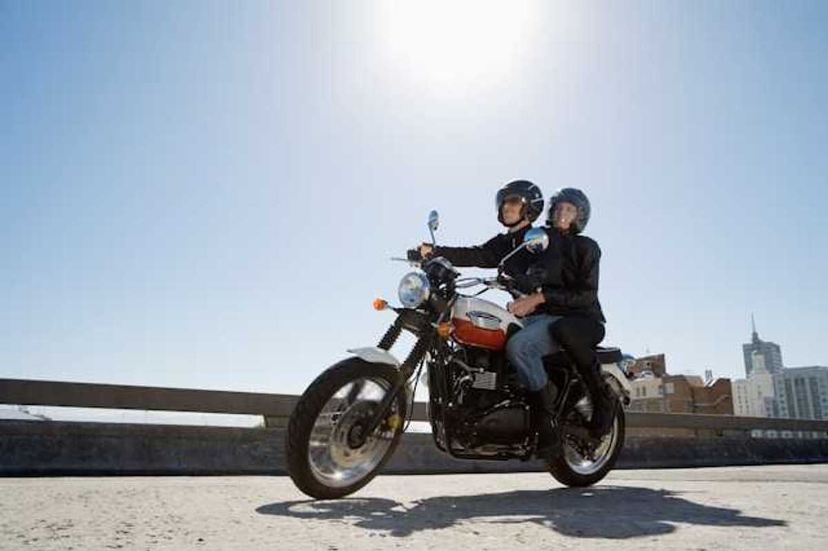 A man and woman riding on a motorcycle on a city street