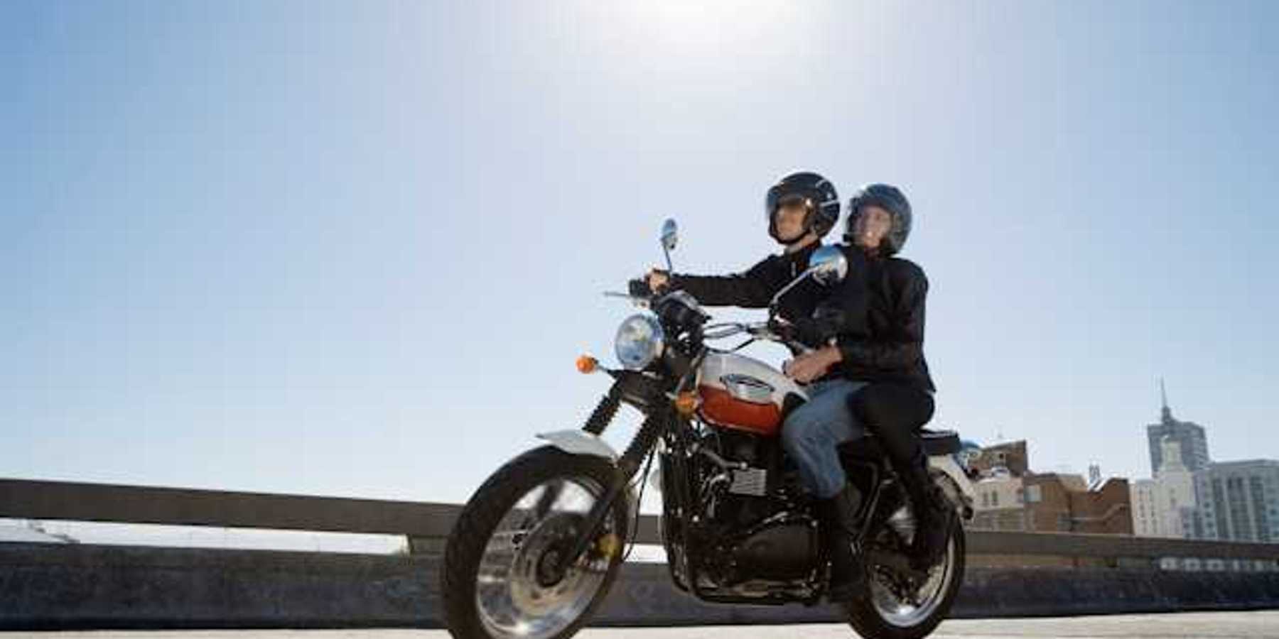 A man and woman riding on a motorcycle on a city street