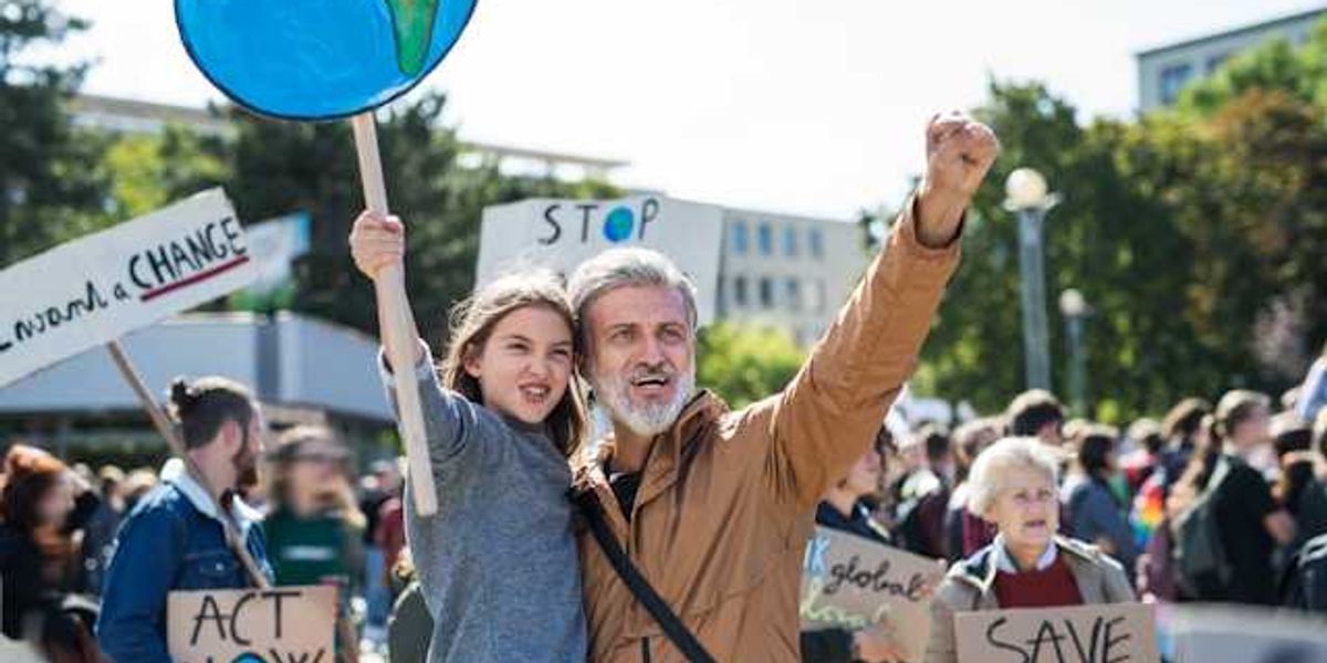 A man holding his daughter during a climate protest