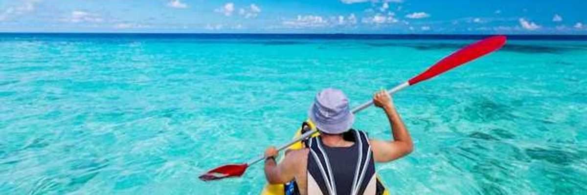 A man in a kayak paddling in turquoise waters