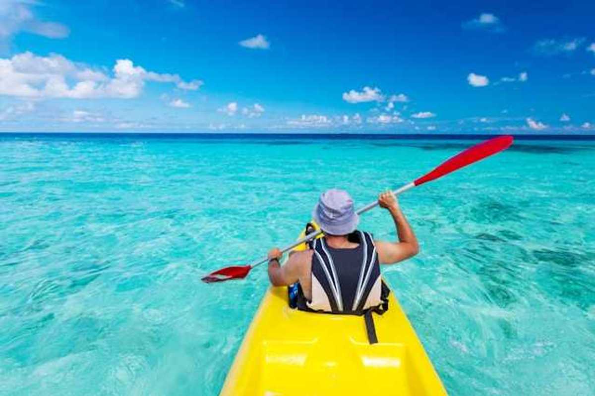 A man in a kayak paddling in turquoise waters