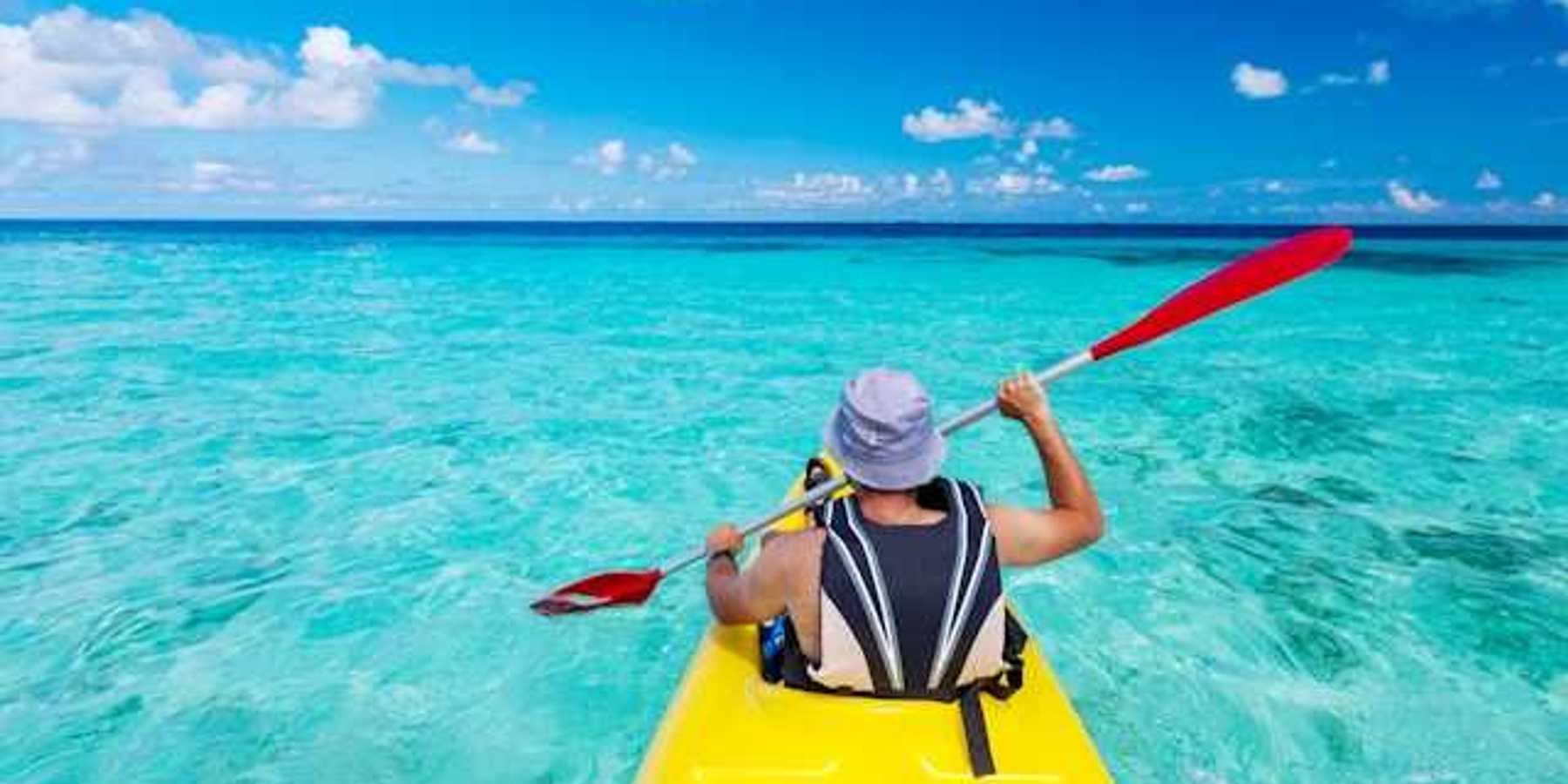 A man in a kayak paddling in turquoise waters