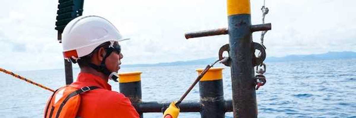 A man in an orange safety vest on an offshore oil rig