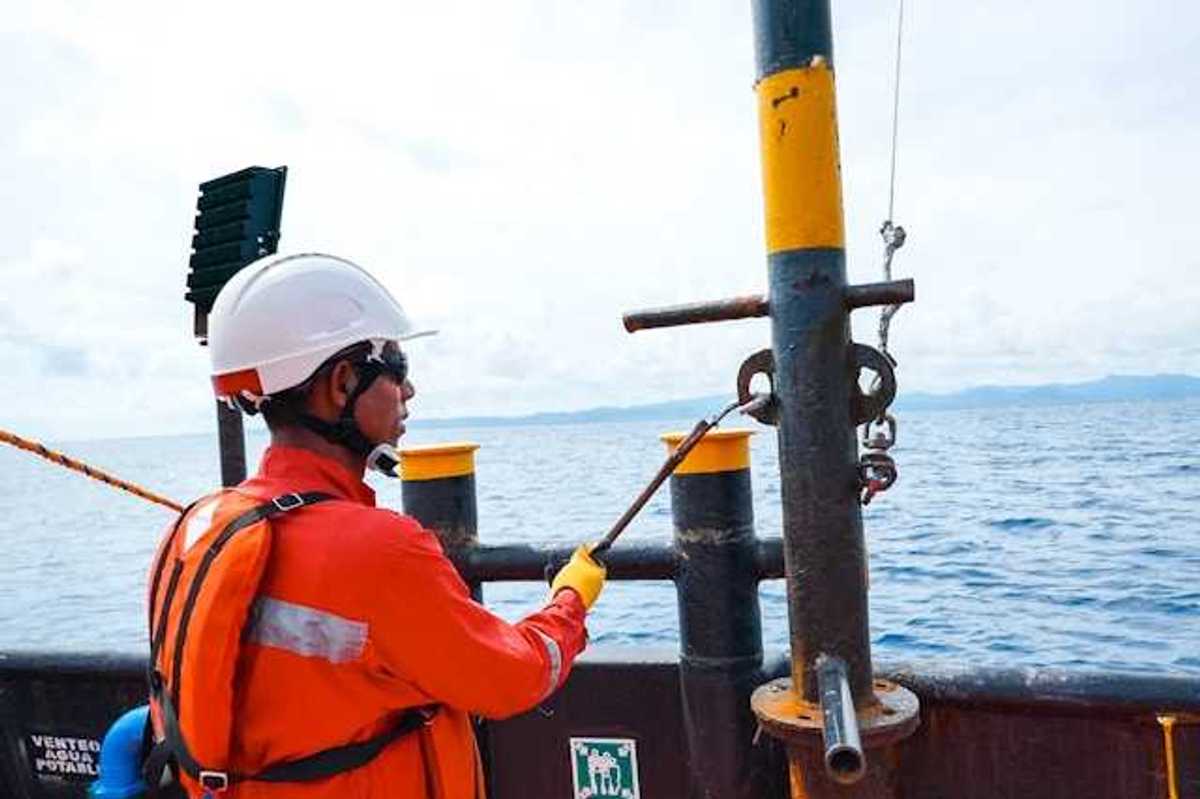 A man in an orange safety vest on an offshore oil rig