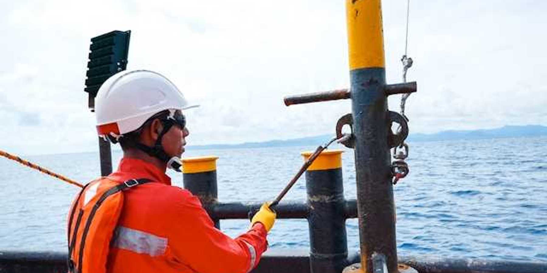 A man in an orange safety vest on an offshore oil rig