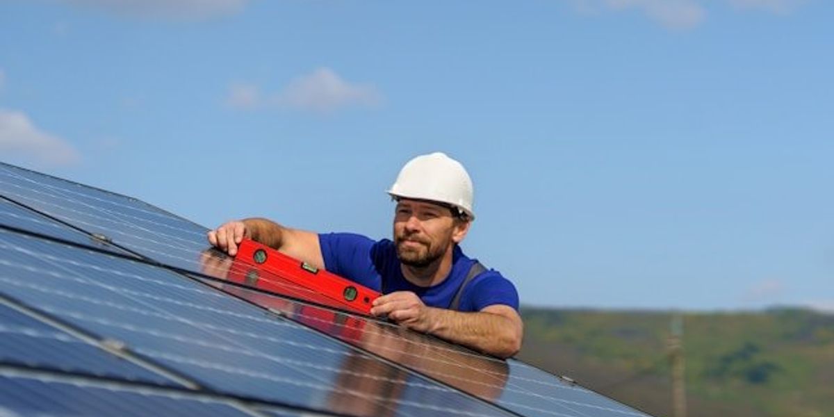 A man installing a solar panel on a roof.