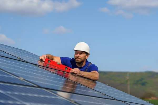 A man installing a solar panel on a roof.