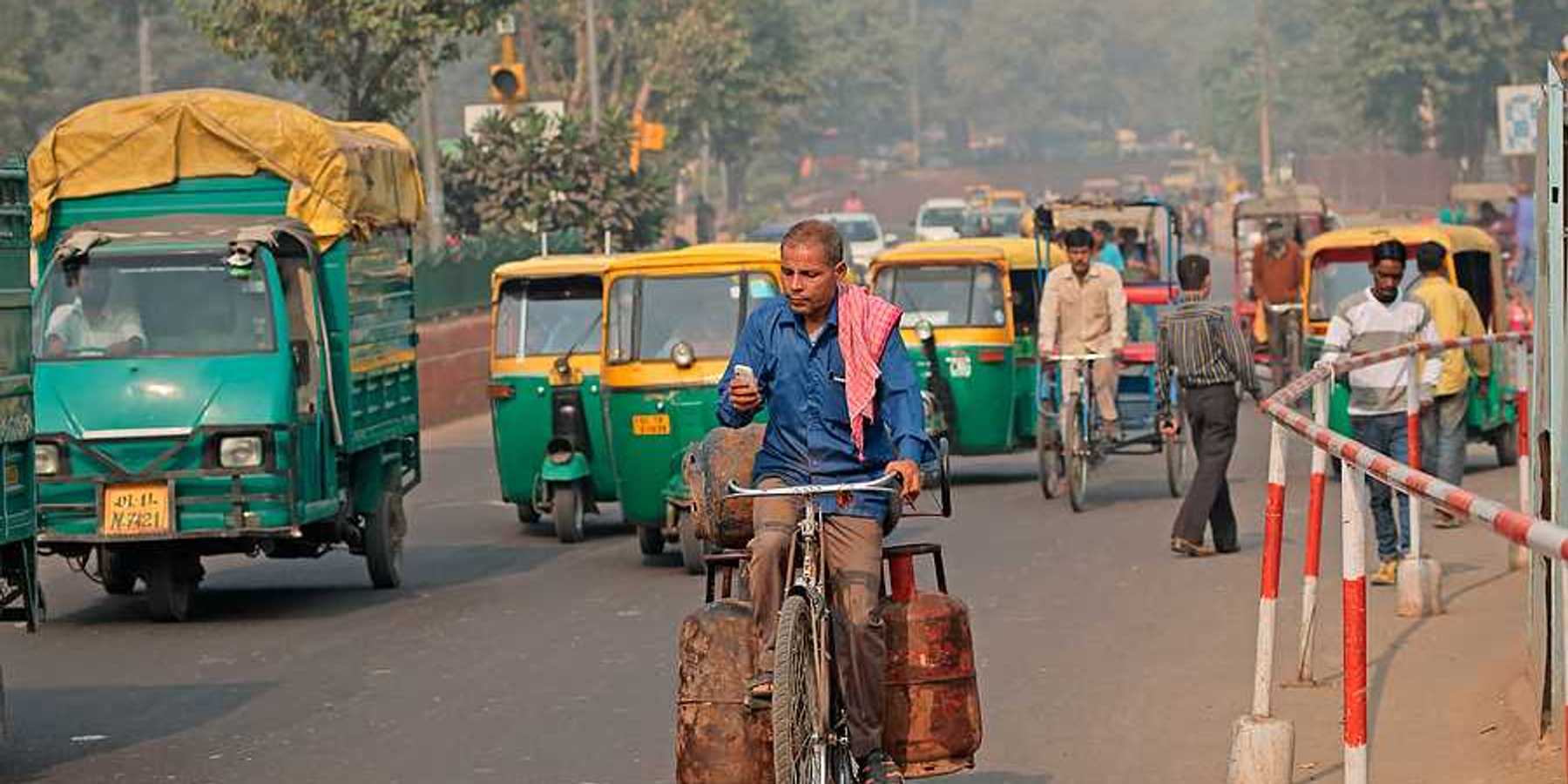 A man on a bike riding through a densely trafficked road in an Indian city