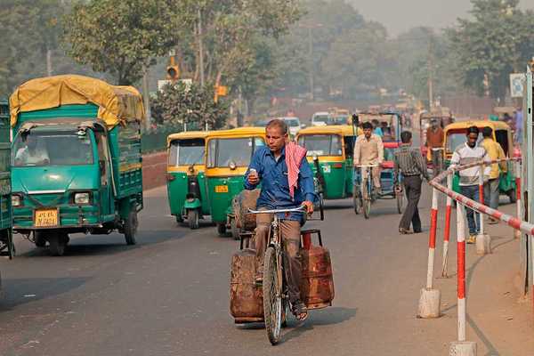 A man on a bike riding through a densely trafficked road in an Indian city