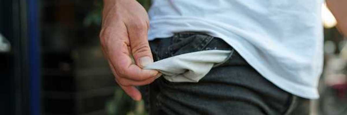 A man pulling out his pants pockets to show that they're empty