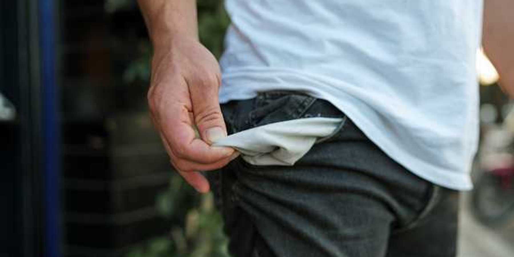 A man pulling out his pants pockets to show that they're empty