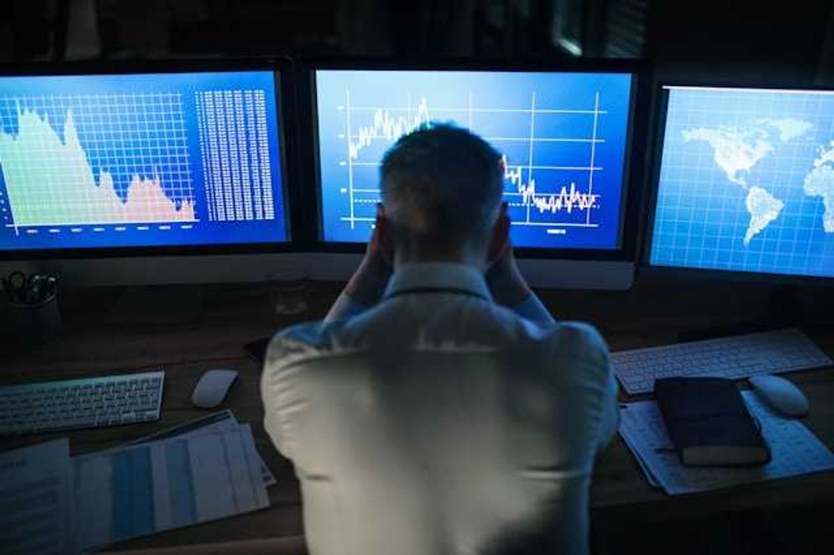 A man sitting in front of computer screens with data charts and maps on the screens