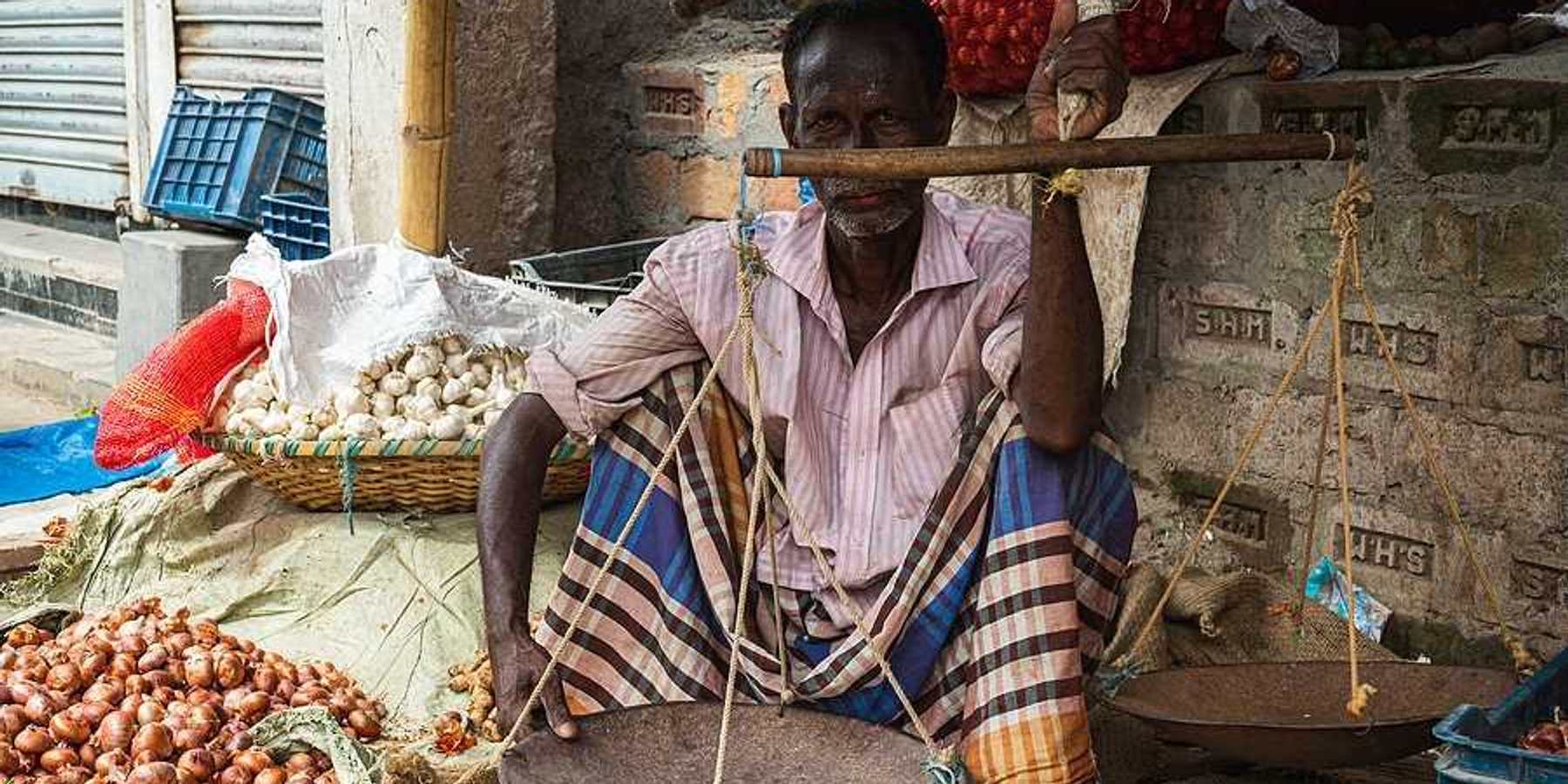 A man sitting on the sidewalk selling onions