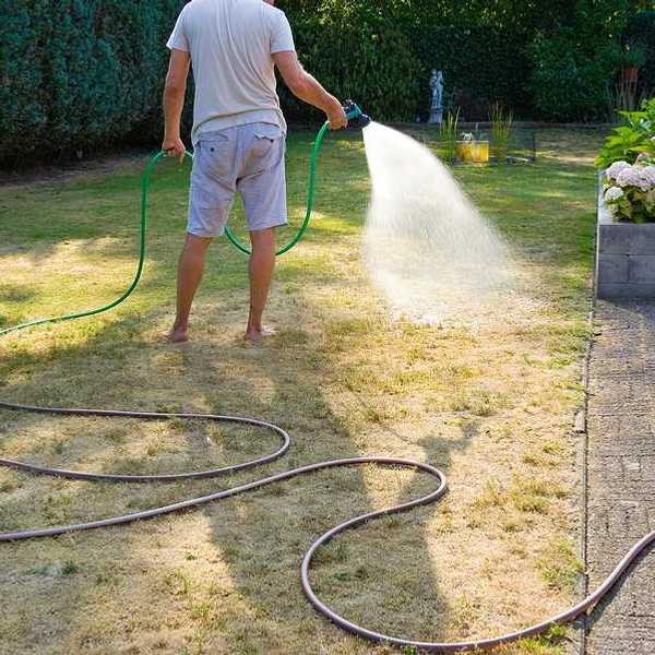 A man using a hose to water a lawn