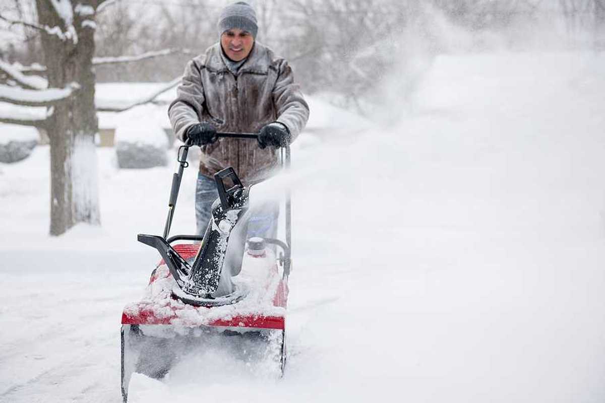 A man using a snow blower on a snowy day