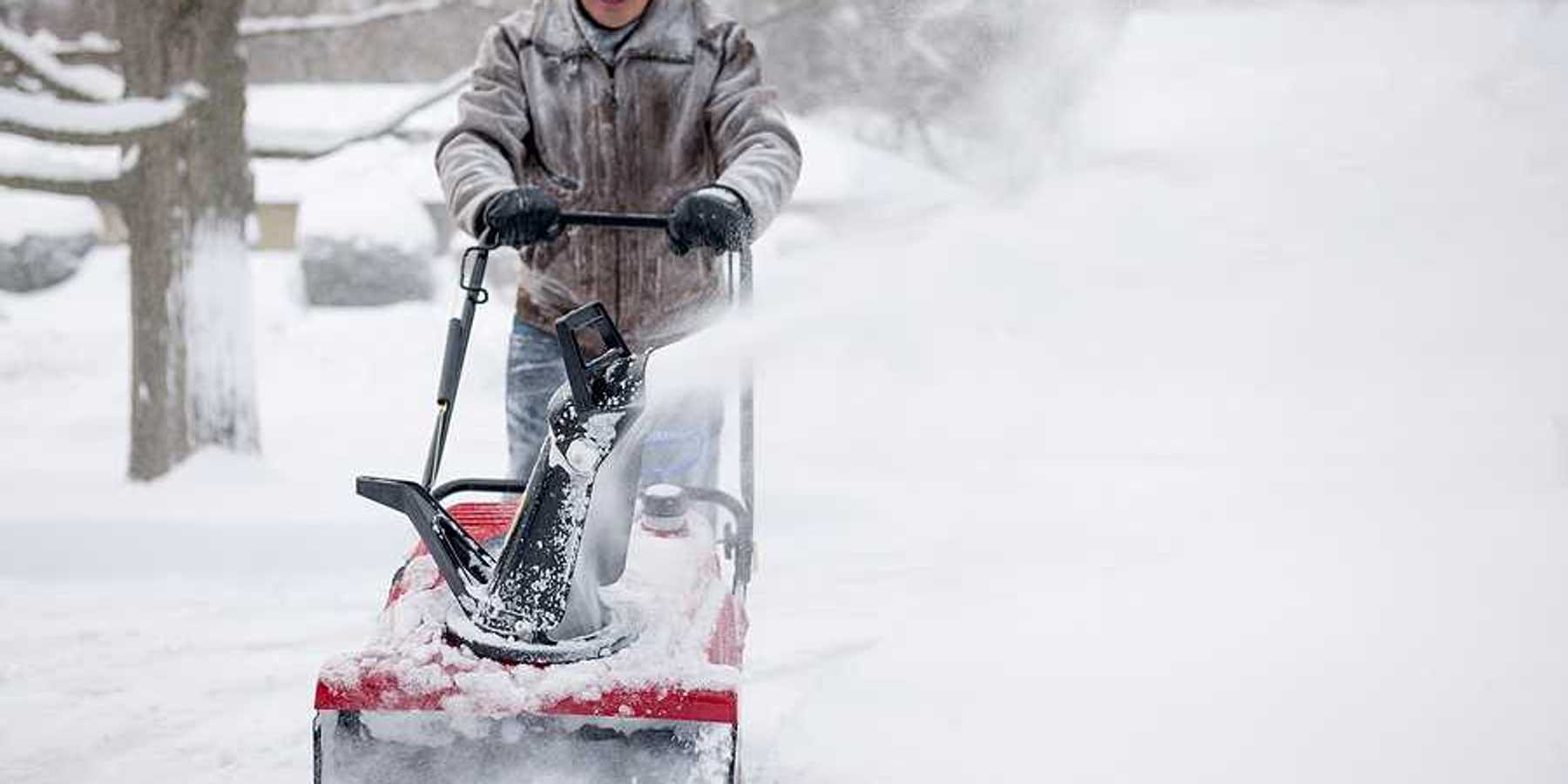 A man using a snow blower on a snowy day