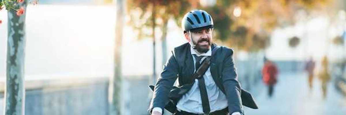 A man wearing a business suit riding his bike to work