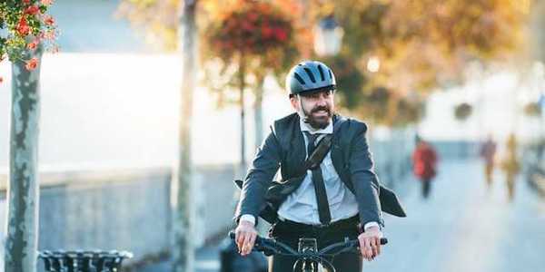 A man wearing a business suit riding his bike to work