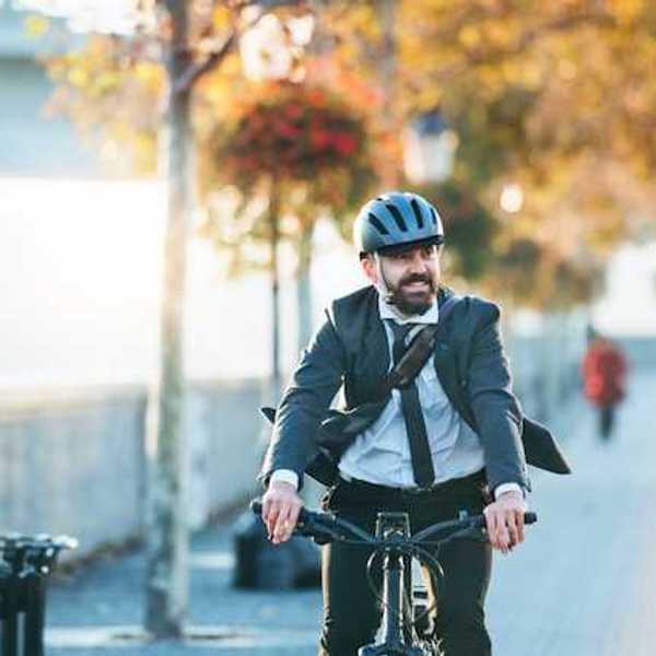 A man wearing a business suit riding his bike to work