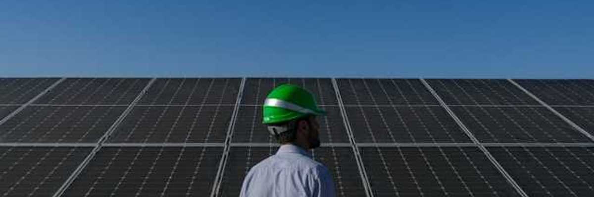 A man wearing a hard hat standing in front of solar panels