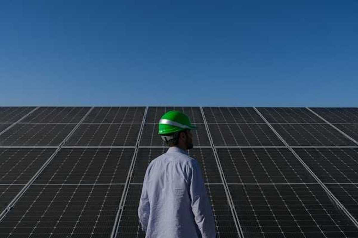 A man wearing a hard hat standing in front of solar panels