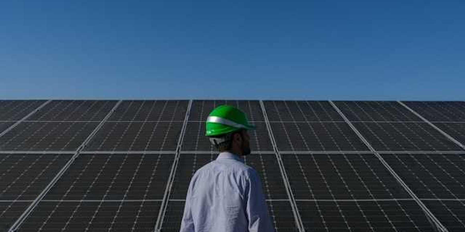 A man wearing a hard hat standing in front of solar panels
