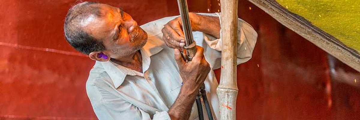 A man welding a piece of metal onto a boat