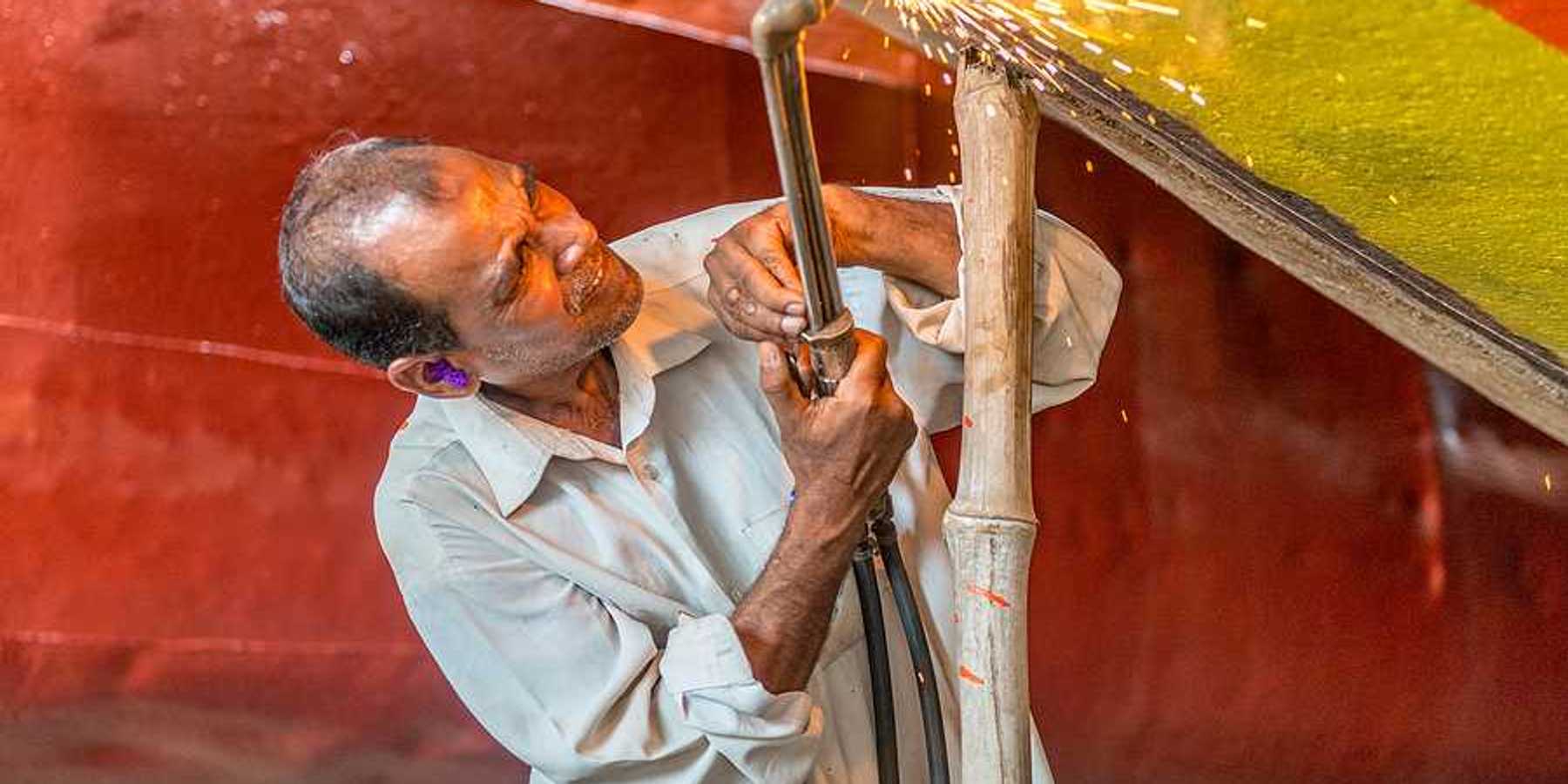 A man welding a piece of metal onto a boat