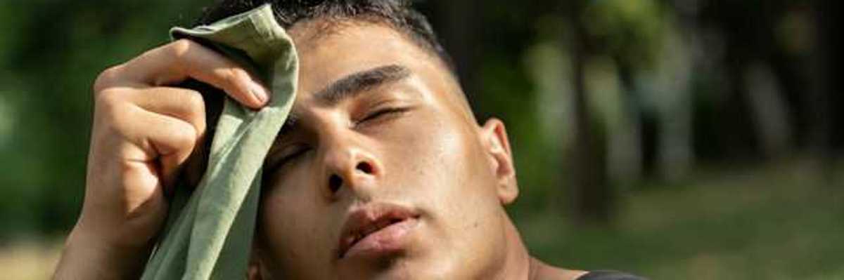 A man wiping sweat from his brow with a green towel