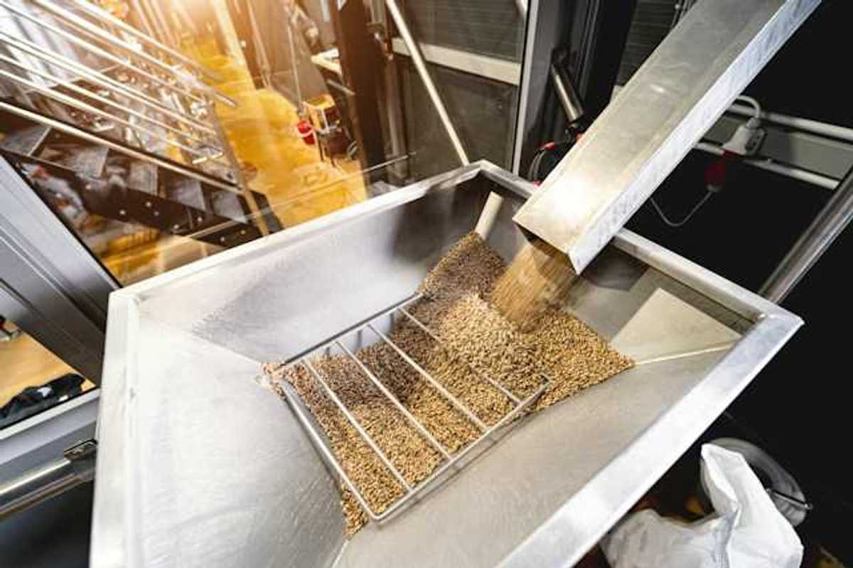 A metal chute delivering wood pellets into another metal container