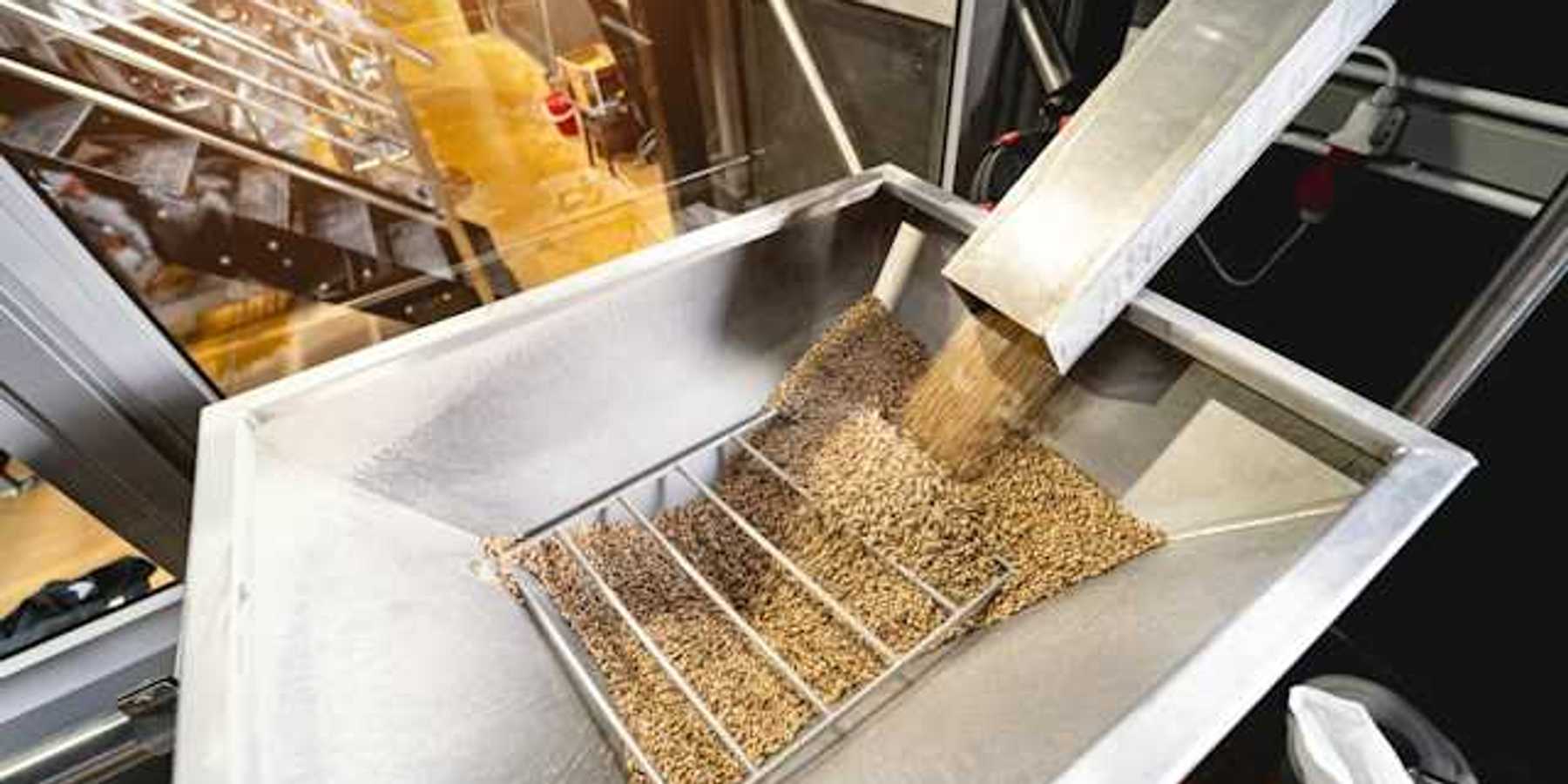 A metal chute delivering wood pellets into another metal container
