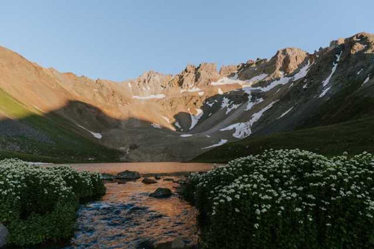 A mountain range with light snow above a lake