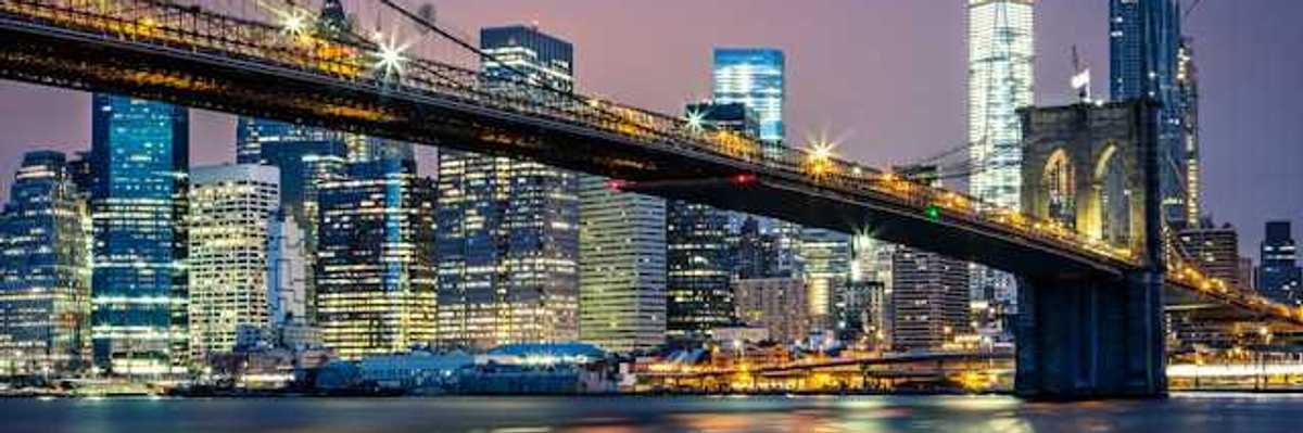 A night time view of the Brooklyn Bridge with the city in the background