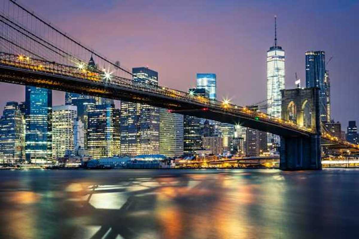 A night time view of the Brooklyn Bridge with the city in the background