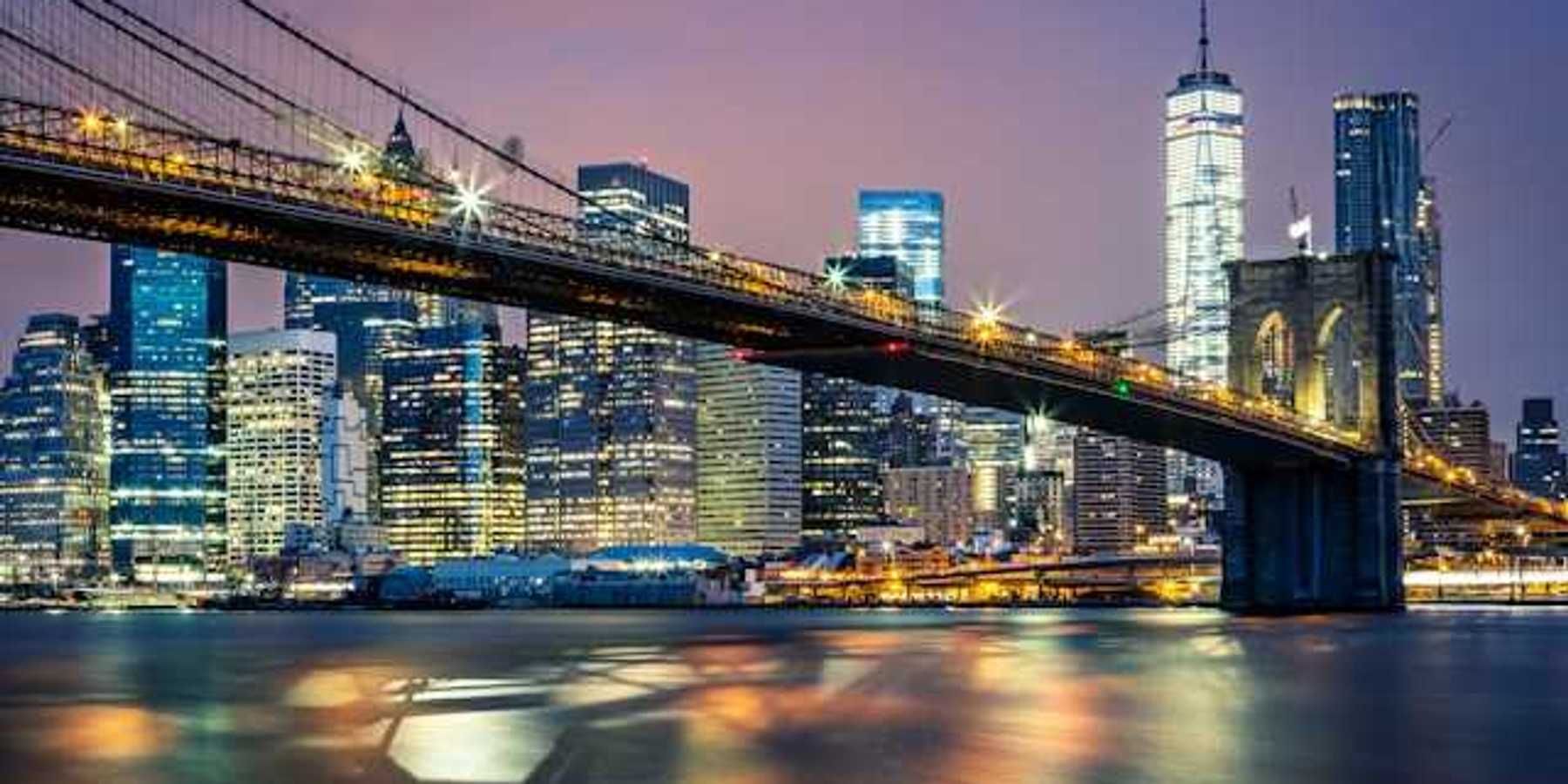 A night time view of the Brooklyn Bridge with the city in the background