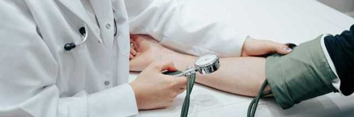 A nurse holding a blood pressure gauge while taking a patient's blood pressure