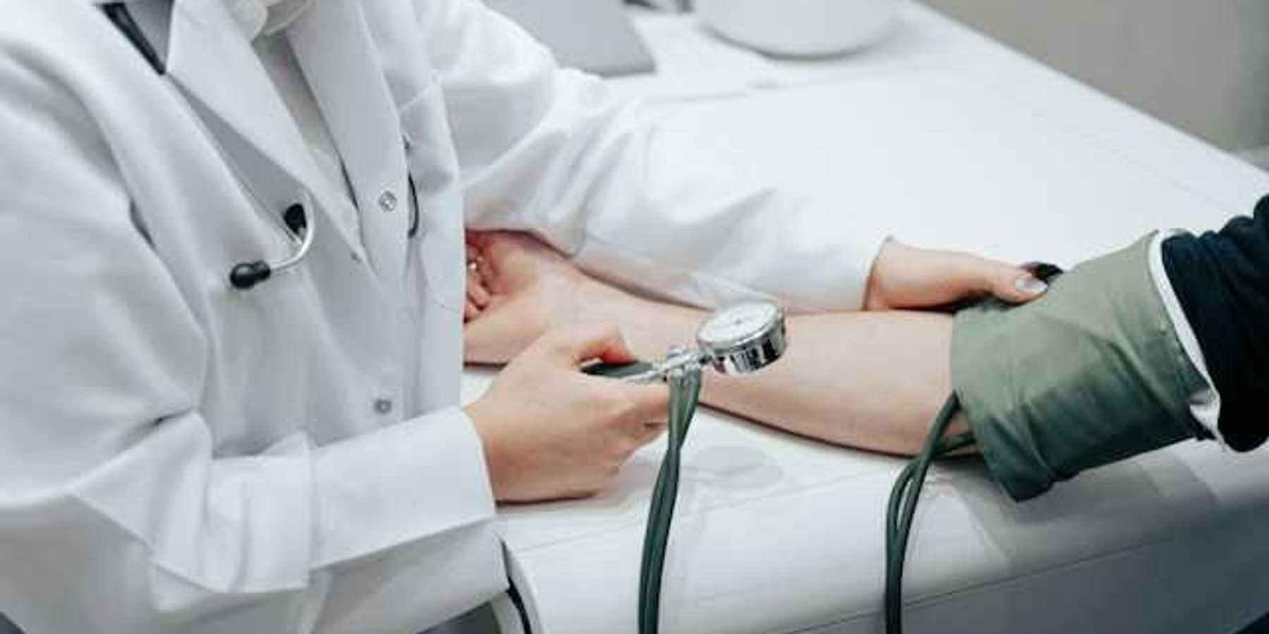 A nurse holding a blood pressure gauge while taking a patient's blood pressure