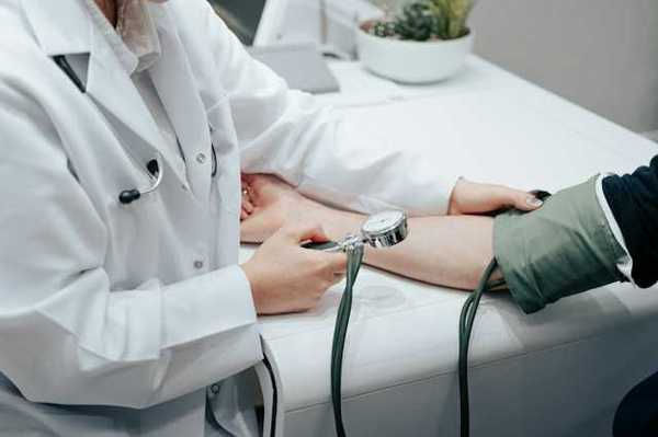 A nurse holding a blood pressure gauge while taking a patient's blood pressure