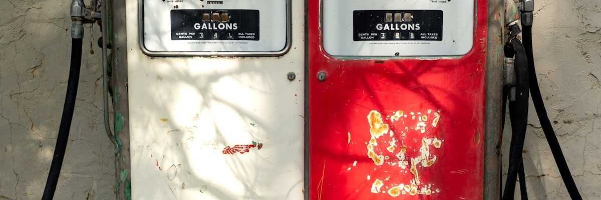 A pair of old gas pumps—one white, one red—juxtaposed side-by-side