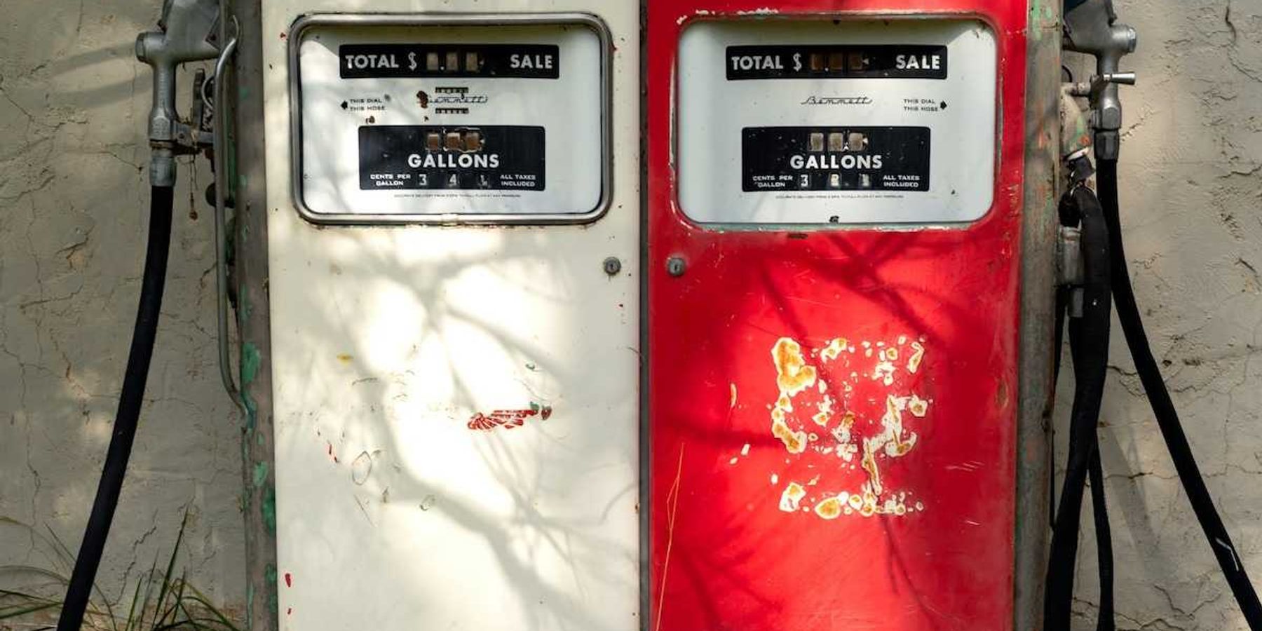 A pair of old gas pumps—one white, one red—juxtaposed side-by-side